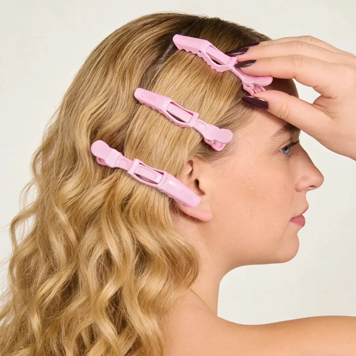 Woman holding wavy hair in place using three pink TYMO Alligator Sectioning Clips along the side of her head